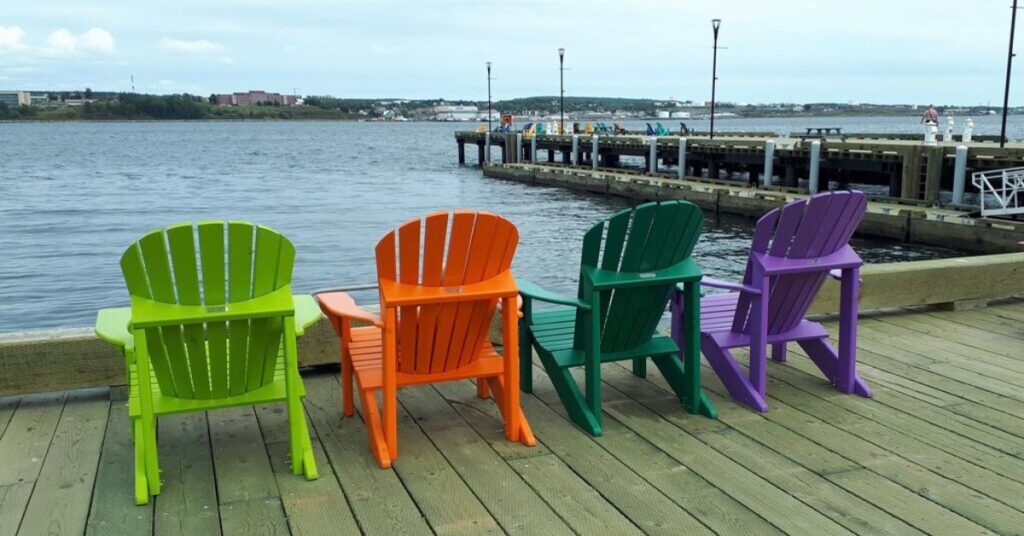 colourful adriondack chairs on a wooden boardwalk on the halifax harbour