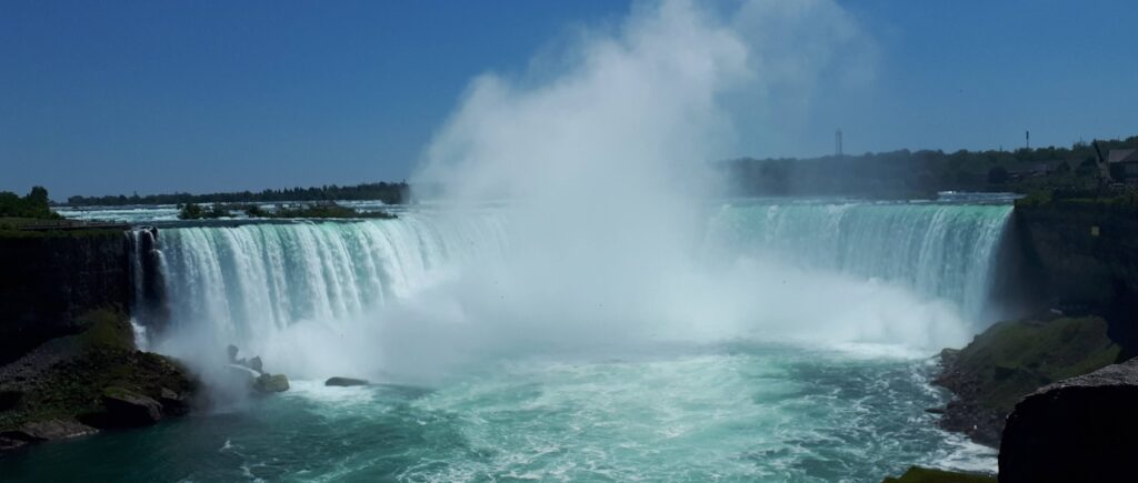 mist coming off a large waterfall as the water falls into the pool below
