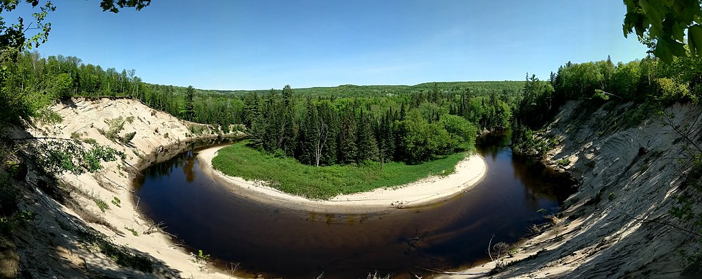 view from lookout point of the big bend in arrowhead provincial park. the water appears dark purple as it rounds the bend and green trees sit in the bend the water creates