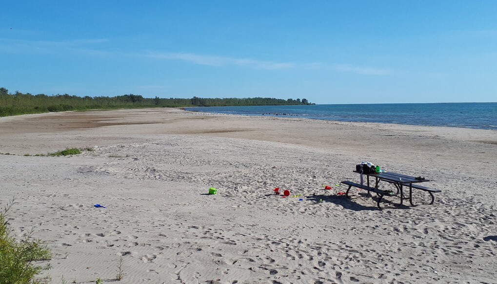 a large white sand beach as seen from the edge of the beach looking out to the blue water in the distance