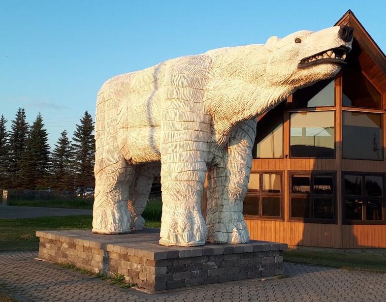 a large white polar bear statue stands beside a building in cochrane ontario