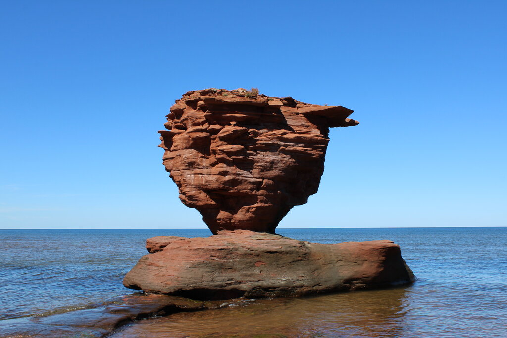red sandstone rock formation that resembles a teacup - called the teacup rock at thunder beach in pei
