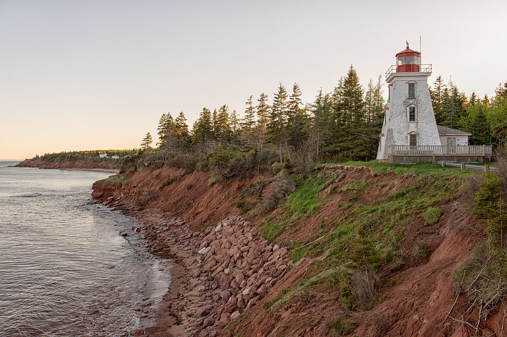 white lighthouse perched on the edge of a cliff in PEI