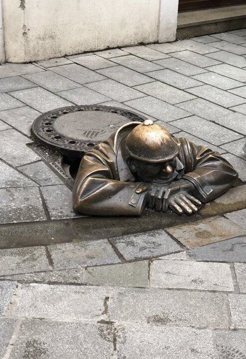 statue of a man emerging from a sewer