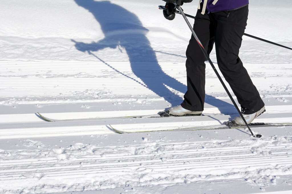 view from the waist down of a person cross country skiing, with a shadow projected onto the snow
